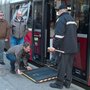 Ein Mann hat die Rampe bei einer Türe eines Busses ausgeklappt, damit der Rollstuhlfahrer aussteigen kann.