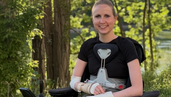 Céline sitzt im Elektrorollstuhl auf einem Waldspaziergang